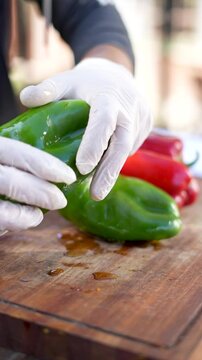 Rubbing green peppers with morron olive oil while wearing white gloves
