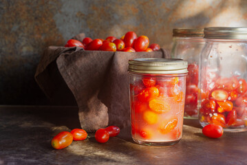 lacto fermented cherry tomatoes in a glass bottle jar on brown rustic table.