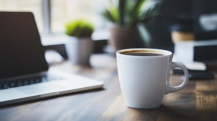 A coffee cup and a laptop on an office desk, surrounded by a calm, organized workspace, with plenty of room for copy.