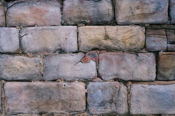 Old stone wall showing deterioration and colorful patina