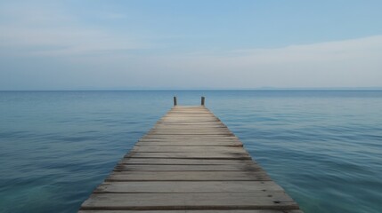 Obraz premium Serene wooden pier extending into calm blue sea under a tranquil sky.