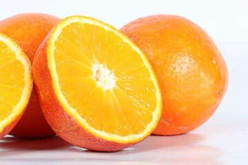 Several whole oranges and halved oranges arranged on a white background