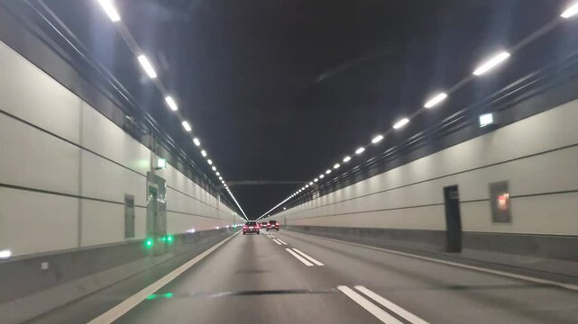Driving through a well-lit tunnel with smooth asphalt and illuminated walls at night