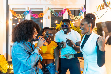Latin man singing karaoke enjoying with friends at home party