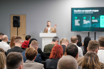 Conference speaker presenting to a focused audience during business seminar in modern venue....