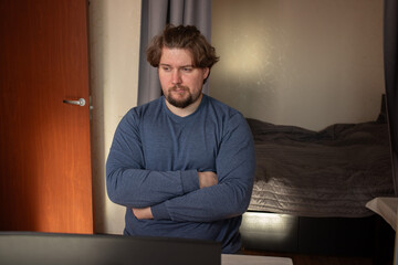 Sad man working on laptop, reacting to a stressful situation at a table, focusing on a freelance task in a casual environment.