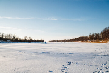 In a picturesque snowy field, there are distinct footprints imprinted in the abundant snow, while trees stand majestically in the background, creating a serene winter landscape