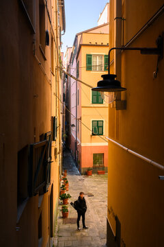 Fototapeta Perspective view on downhill thin street with tourist in Genoa, Liguria, Italy. Famous thin streets in Genova