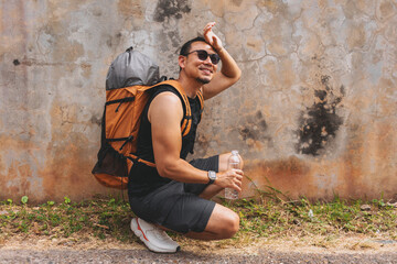 Tourist backpacker man resting drinking water as Asia sun is too hot.