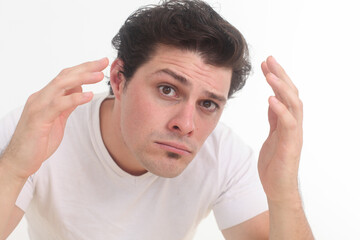Fototapeta premiumSerious handsome young man checking his appearance looking at camera - concept of Skin care, hair, and face protection.