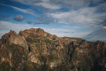 Towering cliffs reveal rugged rock formations and lush greenery, illuminated by the soft glow of...
