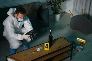 Forensic expert with camera taking photo of evidences at crime scene indoors