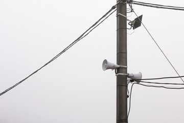 A Loudspeaker On A Pole With Wires On A Cloudy Day