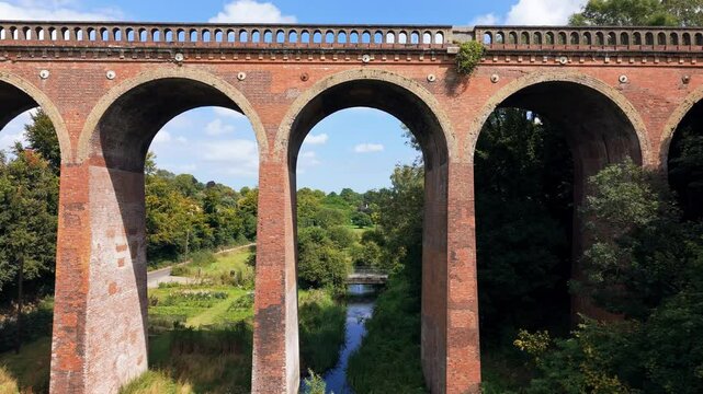 Aerial dolly forward through Viaduct archways, rural England landmarks
