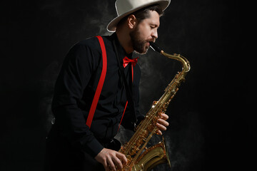 Professional musician playing saxophone on black background with smoke