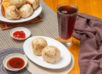 Pan Fried Buns 2 piece with Dipping Sauces and a tall glass of iced tea isolated on napkin side view of taiwan dim sum food