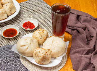 2 Steamed Buns, 2 Friend Buns with Dipping Sauces and a tall glass of iced tea isolated on napkin side view of taiwan dim sum food