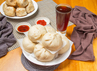 6 steamed pepper meat buns with Dipping Sauces and a tall glass of iced tea isolated on napkin side view of taiwan dim sum food