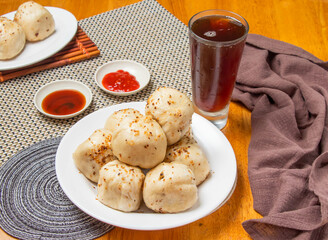 Pan Fried Buns 6 piece with Dipping Sauces and a tall glass of iced tea isolated on napkin side view of taiwan dim sum food