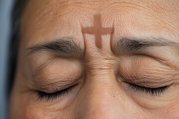 Close-up of forehead with ash cross symbol on mature woman during Ash Wednesday