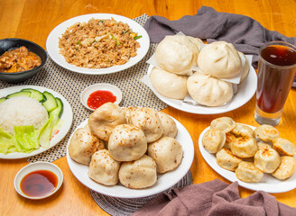 Assorted Buns, pork meat bun, pan fried buns, Egg Fried Rice, Lemongrass Chicken Rice, ice black tea and dipping sauce served in plate isolated on table side view of dim sum taiwan food