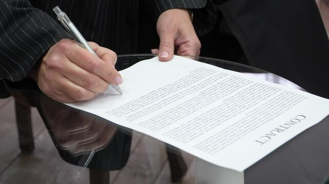 Signing a Contract with a Fountain Pen on a Glass Table