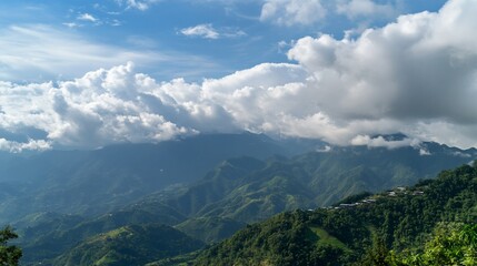 Obraz premium Majestic Mountain Range with Clouds and a Small Village on a Green Slope