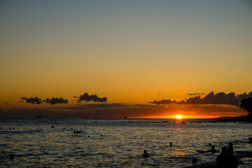 海に沈む美しい夕日とシルエットの人々