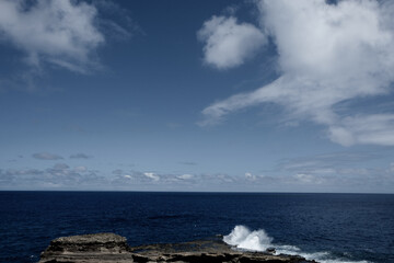荒々しい波が打ち寄せる岩場と深い青の海
