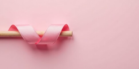 Soft pink ribbon coiled around a wooden dowel, minimalist, craft