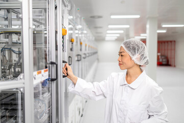 Japanese engineer standing by highly sophisticated industrial machine producing computer chips and electronic components.