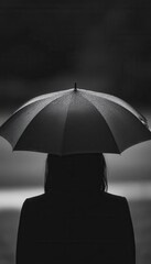 Silhouette of a person under a rain-soaked umbrella.