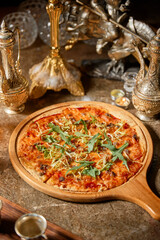 pizza on a tray stands on the table surrounded by many decorative items