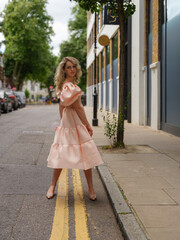 A fashionable woman in a pink dress with puffed sleeves walks gracefully down a city street, exuding confidence and elegance with a soft, flowing movement