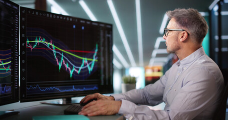 Stock Market Broker Looking At Graphs On Multiple Screens