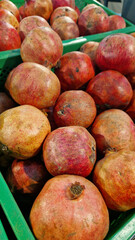 Ripe pomegranate fruits for sale in a supermarket. Pomegranate fruits close-up with selective focus. Berry-like fruit. Pile of delicious pomegranates for sale in a store. Variety of fresh produce