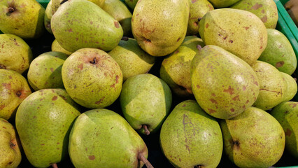 Ripe pears for sale in a supermarket. Pears close-up with selective focus. Fruits. A pile of pears for sale in a store. A variety of fresh fruits on a supermarket counter