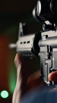 Vertical video Man holds assault rifle, enjoying recreational shooting experience in firing range. Person practices with semiautomatic weapon in safe environment at shooting range company, camera A