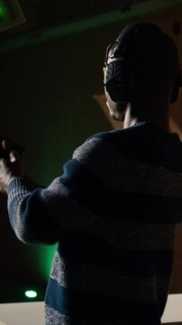 Vertical video Man holds pistol, enjoying recreational shooting experience in firing range next to instructor reloading weapons. Employee loading firearms for shooting range company customers, camera
