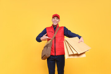 Happy postman with bag pointing at envelopes on yellow background