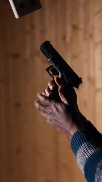 Vertical video Man holds pistol, enjoying recreational shooting experience in firing range next to instructor reloading weapons. Employee loading firearms for shooting range company customers, camera