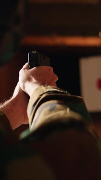 Vertical video Man enjoying recreational shooting experience in firing range, checking if he shot bullseye. Person practicing with weapons in safe environment at shooting range company, hitting