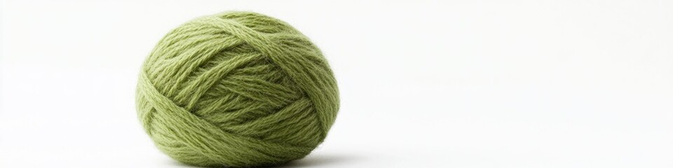 Fototapeta premium A small ball of green yarn on a clean white surface, perfect for crafts and DIY projects