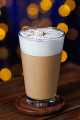 cappuccino in glass with grated chocolate sprinkle on the table with bokeh