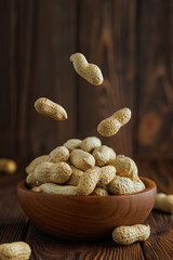 unshelled peanuts falling in bowl on table