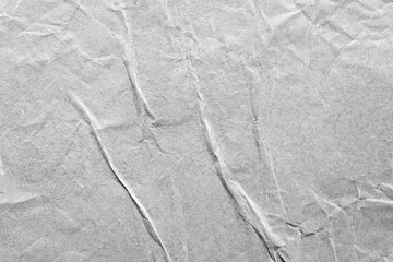 Gray wrinkled paper texture with subtle folds and creases, ideal for design projects or artistic overlays.