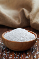 sea salt in wooden bowl on table with burlap on the background