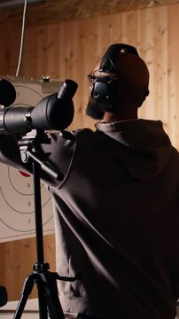 Vertical video Friends in firing range doing recreational shooting, using magnifying lens to see targets. People training with handguns, sharpening skills, zooming to check points scored on bullseyes