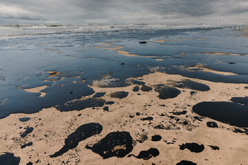 Oil leak in coastline after a tanker wreck. Fuel oil destroy and polluted beach
