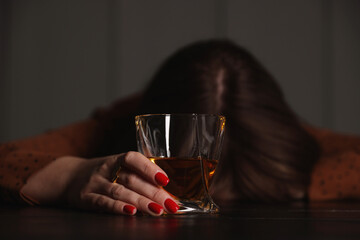 Alcohol addiction. Woman with glass of whiskey at wooden table indoors, selective focus